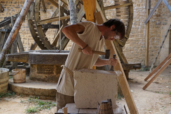 Guédelon, Tailleur de pierre dans la cour du chateau-avec le puits et la cage à